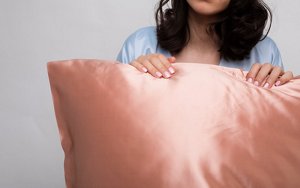 Woman holding a pink silk pillowcase