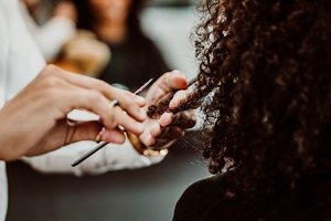 Woman with tight coily hair having her hair cut at the hairdressers