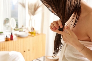 Woman running a lightweight hair serum through damp hair