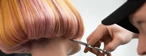 short modern hair style with pink hair showing stylist cutting hair with scissors 