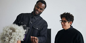 Two hair stylists looking happy at styled person