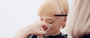 stylist cutting blonde hair with scissors and comb