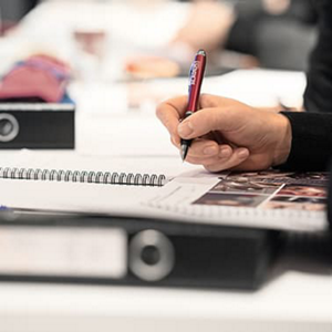 Hand holding pen over paper with pictures