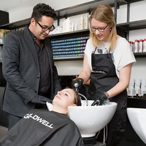 Woman getting hair washed by hairdresser and man standing beside