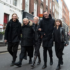 Group of five people on the street wearing all black and smiling