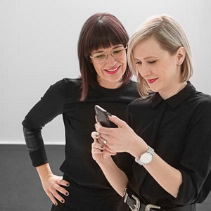 Two female hair stylists looking at smartphone