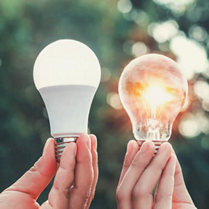 Hands holding one shining light bulb and one light bulb not shining
