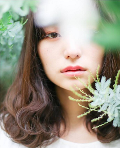 Asian woman with brown hair surrounded by plants