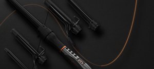 Black VARIS curling iron with four adapters in front of a dark background