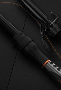 Black VARIS curling iron with four adapters in front of a dark background